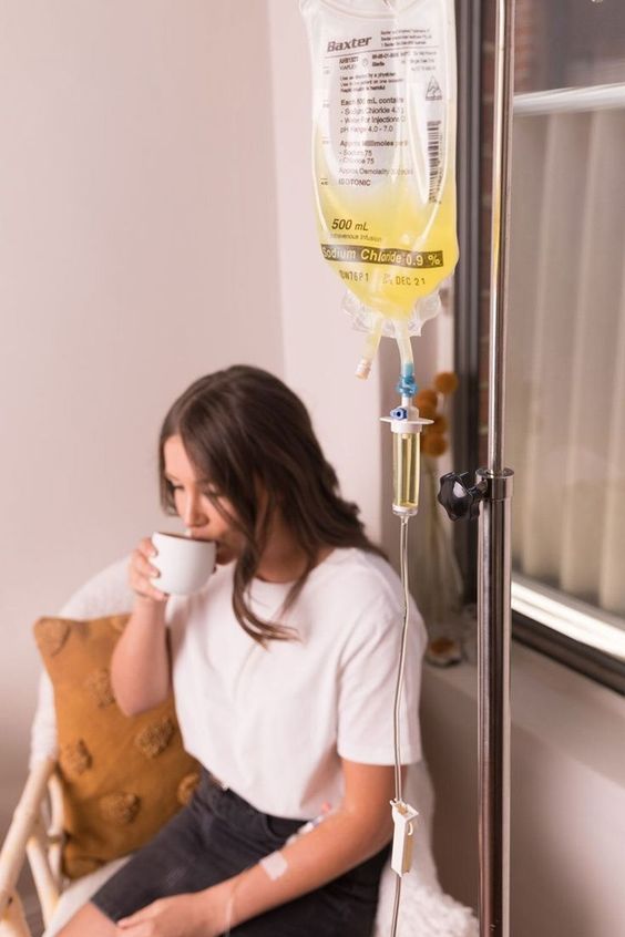 Woman getting a IV Infusion while drinking from a cup
